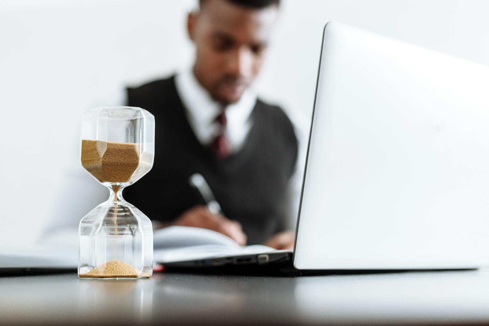 Businessman at desk with hourglass indicating time management and daily work routine.