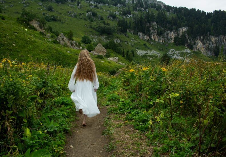 A woman in a white dress walking down a trail